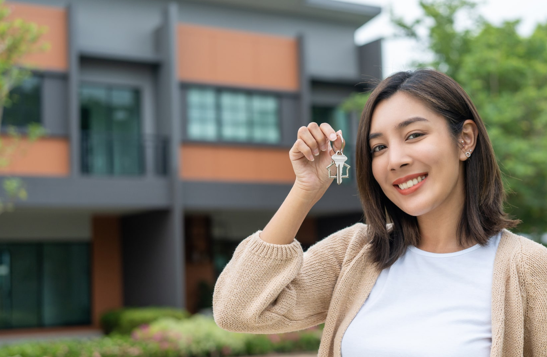 Woman holding key in front of house